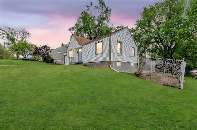 back of property at dusk featuring a lawn and fence