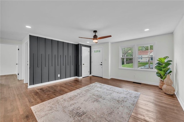 interior space featuring wood finished floors, visible vents, ceiling fan, and baseboards