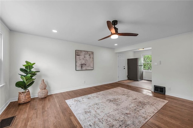 interior space with a ceiling fan, visible vents, wood finished floors, and baseboards