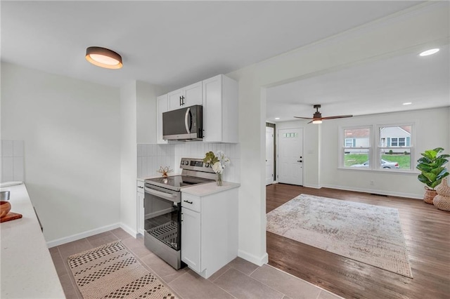 kitchen featuring decorative backsplash, white cabinetry, stainless steel appliances, and light countertops