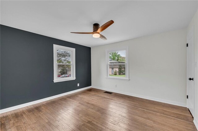 spare room featuring visible vents, plenty of natural light, a ceiling fan, and wood-type flooring