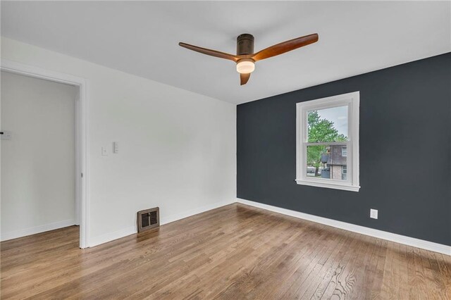unfurnished room with baseboards, visible vents, wood finished floors, and a ceiling fan