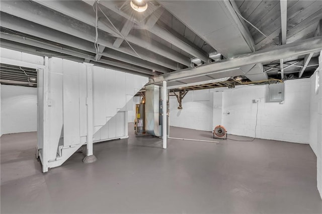 unfinished basement featuring gas water heater, stairway, concrete block wall, heating unit, and electric panel