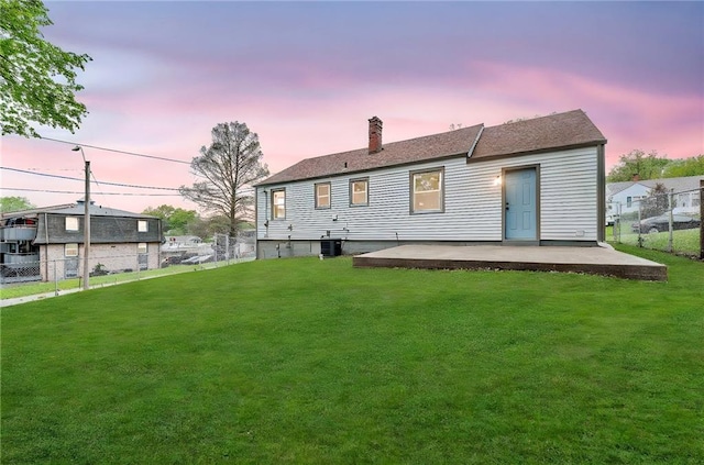 rear view of house featuring fence, a chimney, a yard, and a patio