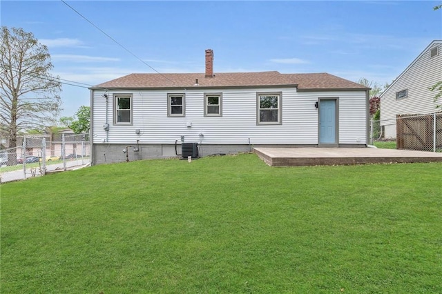 back of house with a lawn, roof with shingles, central AC unit, and fence