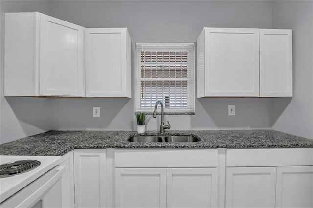 kitchen featuring white cabinets, white range with electric stovetop, a sink, and dark stone countertops