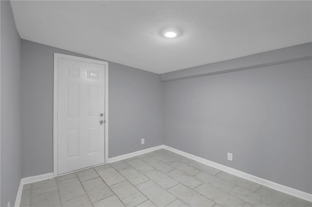 unfurnished room featuring a textured ceiling, baseboards, and vaulted ceiling