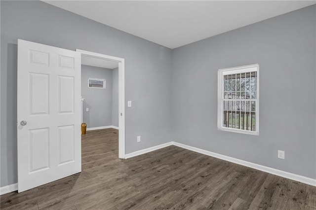 empty room with baseboards and dark wood-style floors