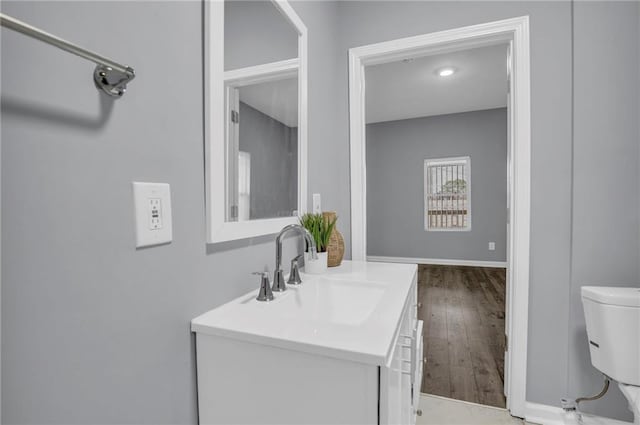bathroom with vanity, baseboards, wood finished floors, and toilet