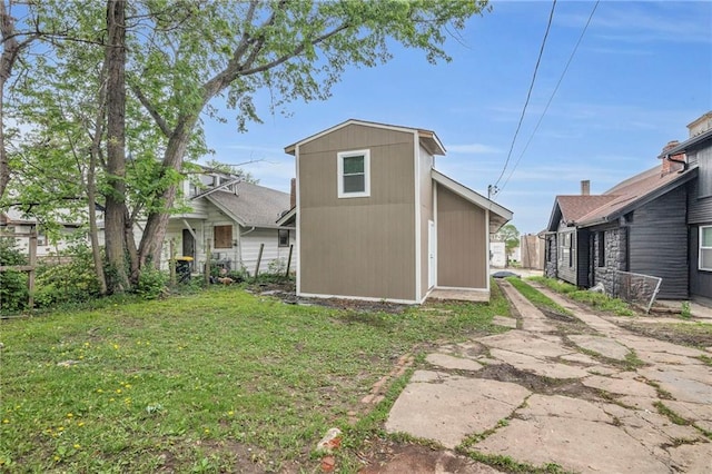 rear view of house with a lawn, fence, an outdoor structure, and a shed