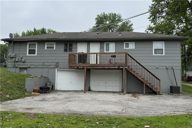 rear view of property with central air condition unit, a garage, stairs, and driveway