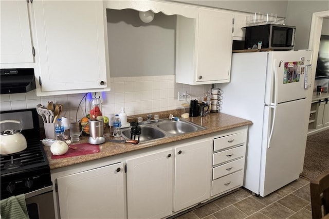 kitchen featuring freestanding refrigerator, gas range, backsplash, a sink, and white cabinetry