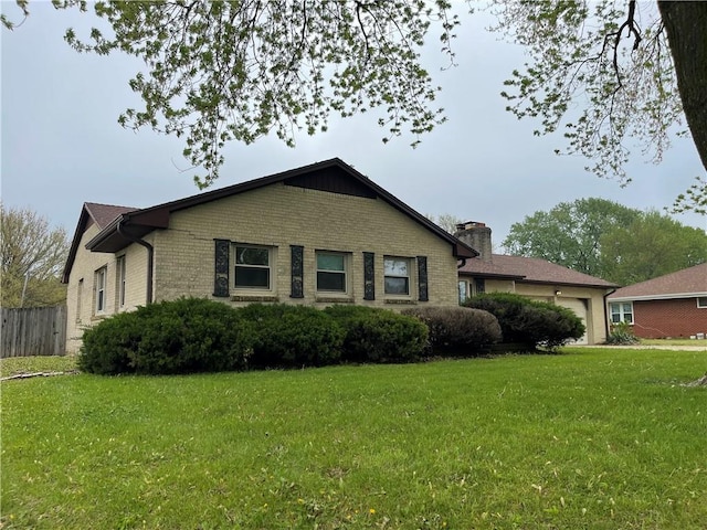 view of property exterior featuring brick siding, a garage, a yard, and a chimney