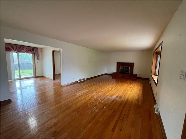 unfurnished living room with baseboards, a fireplace, wood finished floors, and visible vents