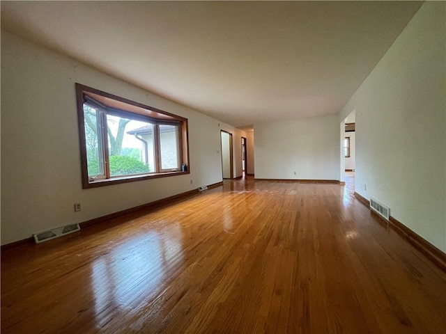 unfurnished living room with visible vents, baseboards, and wood finished floors