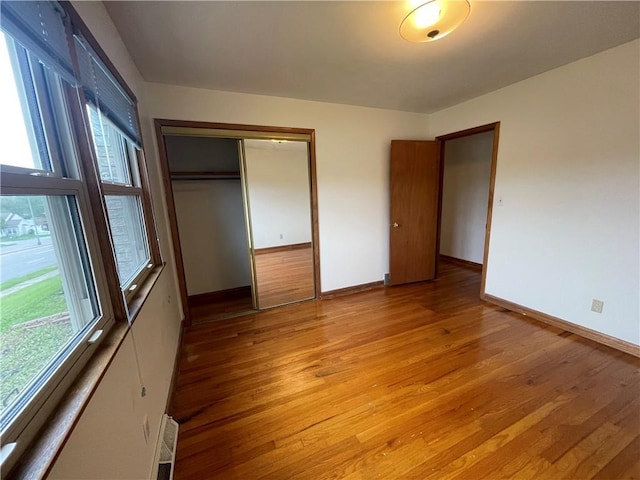 unfurnished bedroom with a closet, baseboards, and light wood-type flooring