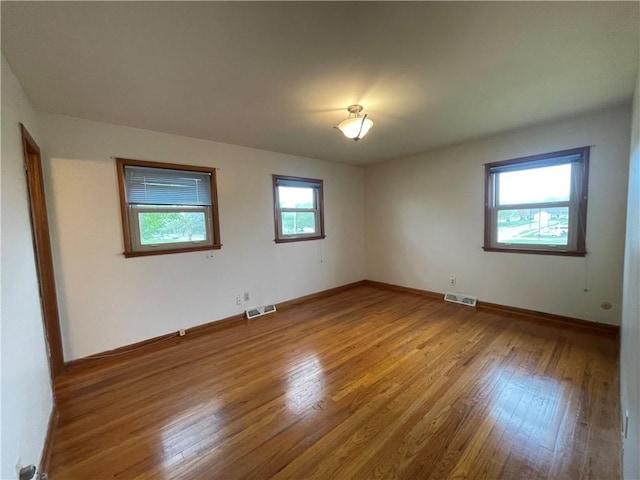 unfurnished room with visible vents, baseboards, and wood finished floors