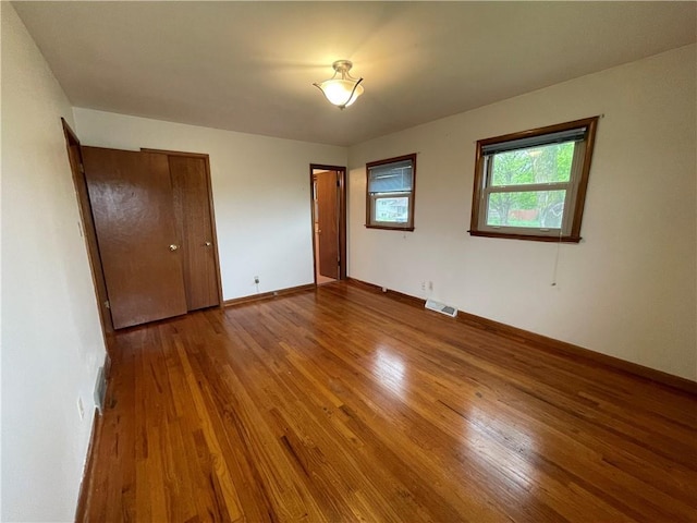 unfurnished bedroom with visible vents, baseboards, and wood finished floors