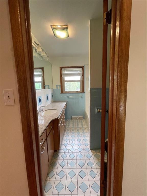 full bathroom with tile patterned floors, a washtub, and vanity