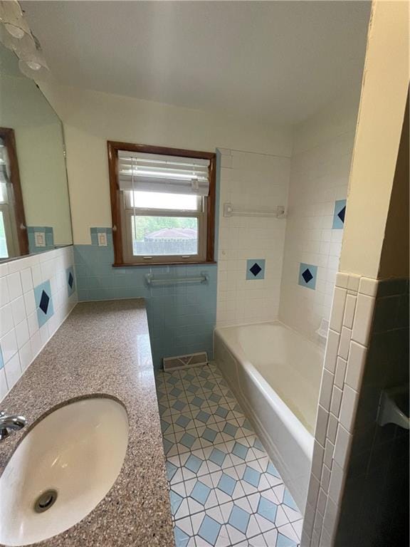 bathroom featuring tile walls, wainscoting, a sink, a bathing tub, and tile patterned floors