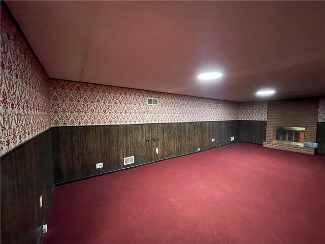 below grade area with visible vents, carpet, a wainscoted wall, and wallpapered walls