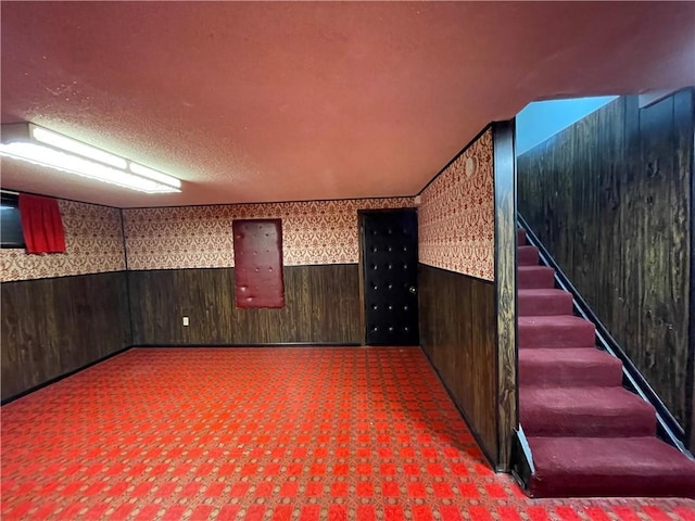 finished basement with stairs, wallpapered walls, wood walls, and wainscoting