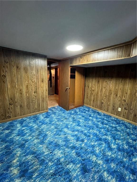 carpeted spare room featuring wood walls