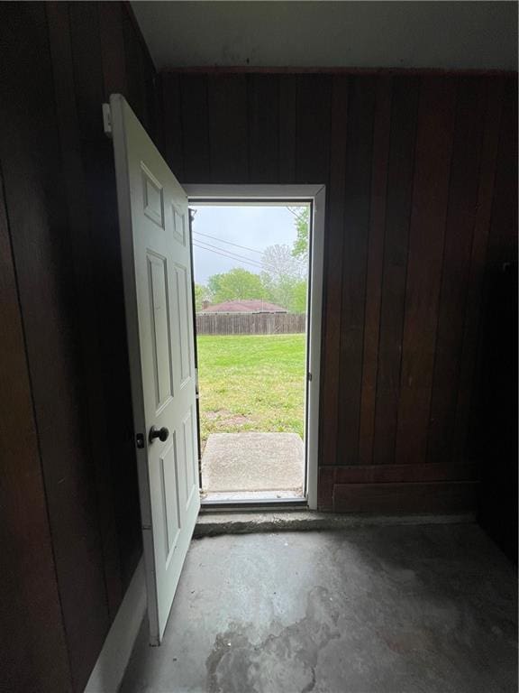 entryway featuring wood walls and unfinished concrete flooring