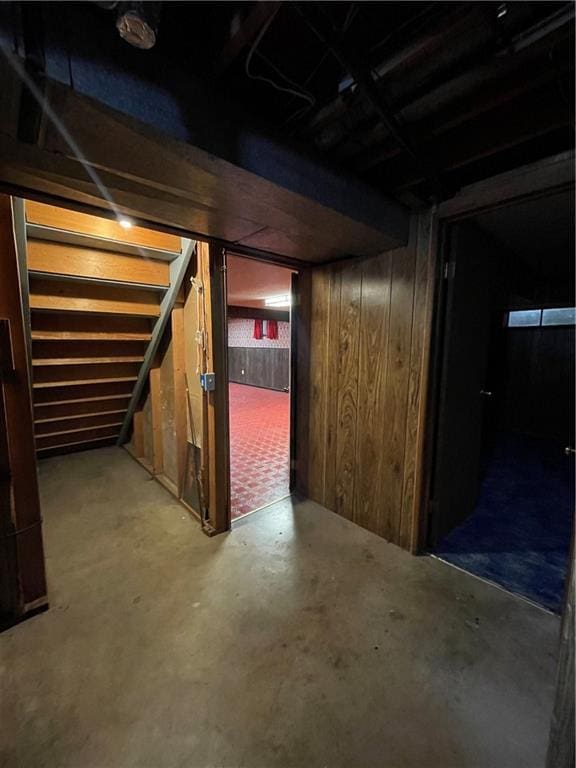 unfinished basement featuring wood walls and stairs