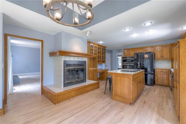 12704 Mohawk Cir, Leawood, KS 66209 - kitchen featuring black fridge with ice dispenser, light wood-style flooring, a chandelier, a kitchen island, and stainless steel double oven