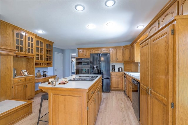 12704 Mohawk Cir, Leawood, KS 66209 - kitchen with black appliances, a kitchen breakfast bar, glass insert cabinets, light countertops, and a center island