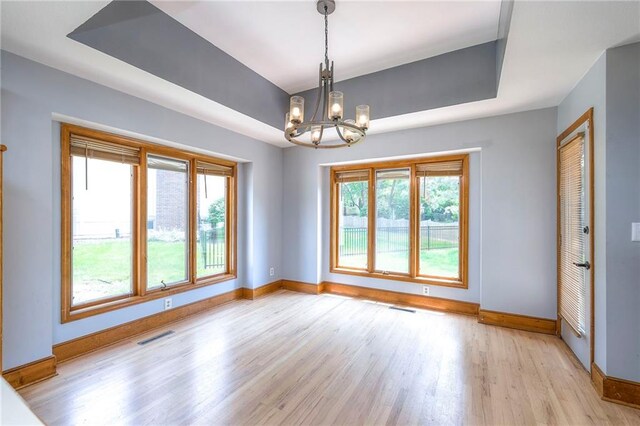 12704 Mohawk Cir, Leawood, KS 66209 - spare room with baseboards, light wood-style flooring, a chandelier, and a tray ceiling