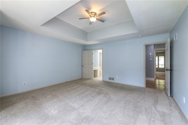 12704 Mohawk Cir, Leawood, KS 66209 - unfurnished bedroom featuring a tray ceiling, light carpet, and baseboards