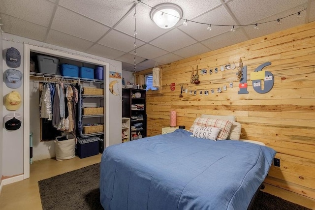 205 N 1700th Rd, Lecompton, KS 66050 - bedroom featuring wooden walls, a closet, a drop ceiling, and concrete flooring
