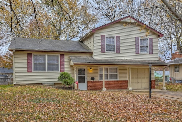 tri-level home featuring a garage, brick siding, fence, and driveway