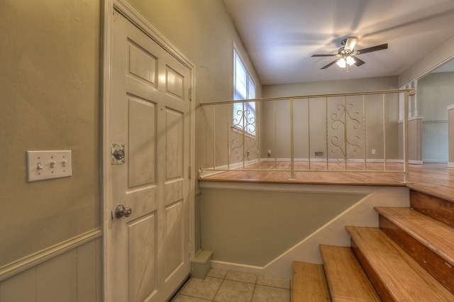 stairs with tile patterned floors and a ceiling fan