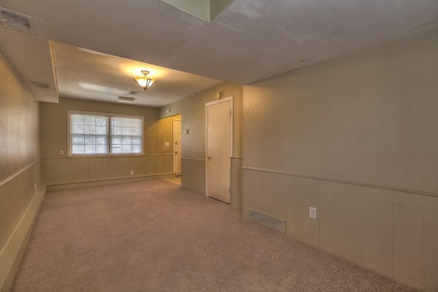 unfurnished room featuring visible vents, wainscoting, and carpet floors