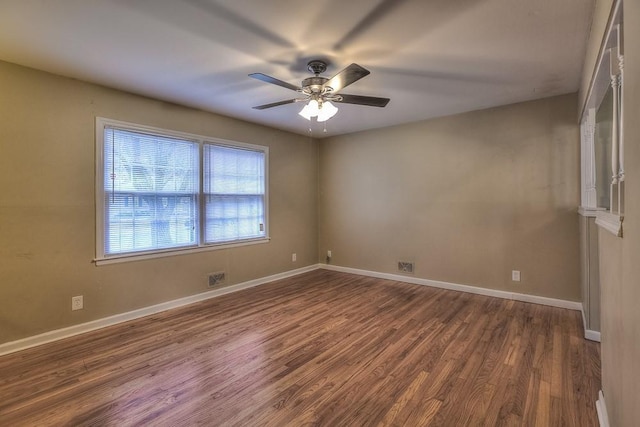 unfurnished room with wood finished floors, a ceiling fan, visible vents, and baseboards