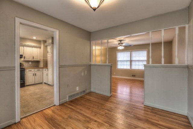 interior space featuring visible vents, a ceiling fan, light wood-style flooring, and baseboards