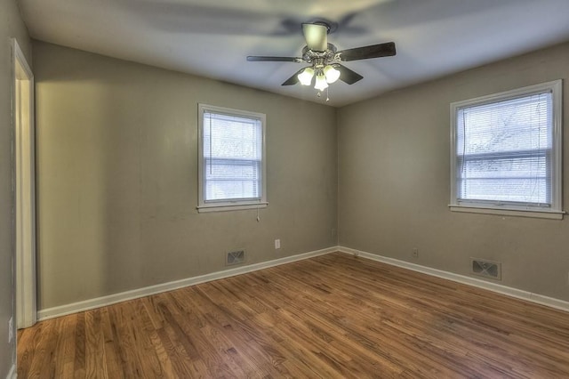 unfurnished room with visible vents, wood finished floors, and plenty of natural light