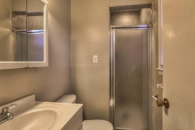 bathroom with a shower stall, toilet, and vanity