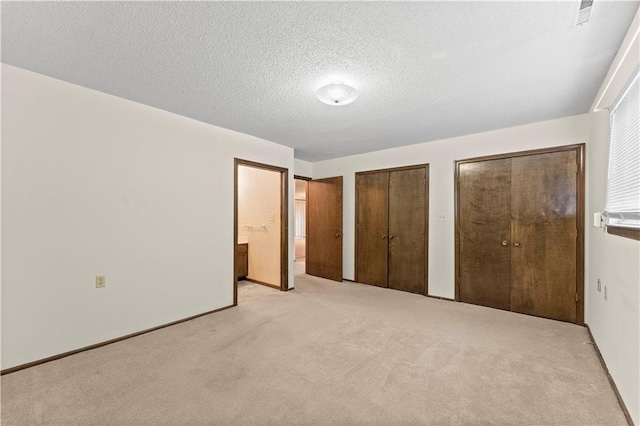 501 N Stone Blvd, Raymore, MO 64083 - unfurnished bedroom featuring carpet floors, a textured ceiling, multiple closets, and ensuite bath