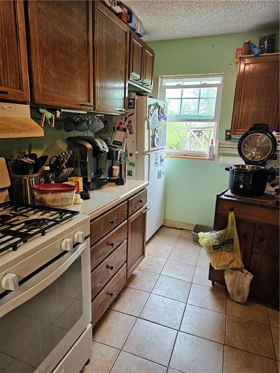 30740 W 83rd St, De Soto, KS 66018 - kitchen with a textured ceiling, light tile patterned floors, light countertops, exhaust hood, and white appliances