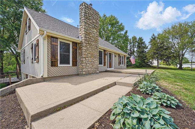 5700 N 123rd St, Kansas City, KS 66109 - rear view of house featuring a chimney, roof with shingles, a lawn, and a patio area