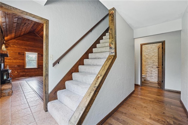 5700 N 123rd St, Kansas City, KS 66109 - stairway featuring lofted ceiling, wooden walls, a wood stove, wood ceiling, and wood finished floors
