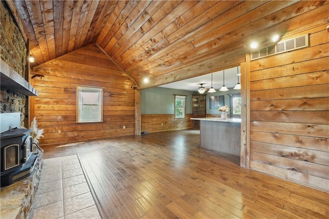 5700 N 123rd St, Kansas City, KS 66109 - unfurnished living room featuring wood walls, a wood stove, hardwood / wood-style flooring, wood ceiling, and healthy amount of natural light