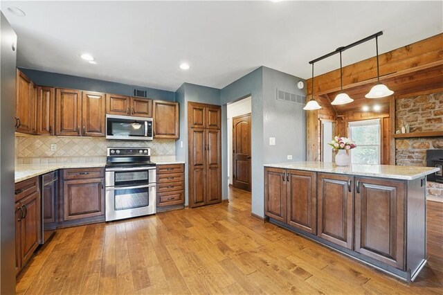 5700 N 123rd St, Kansas City, KS 66109 - kitchen featuring stainless steel appliances, light wood finished floors, backsplash, hanging light fixtures, and light stone countertops