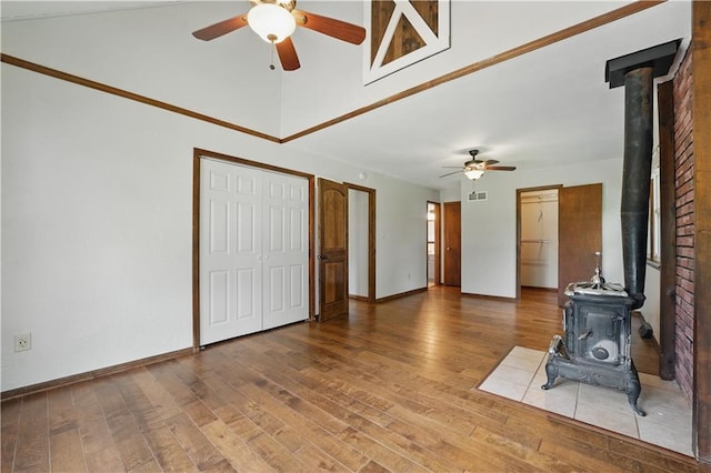 5700 N 123rd St, Kansas City, KS 66109 - unfurnished living room featuring a wood stove, ceiling fan, wood finished floors, and baseboards