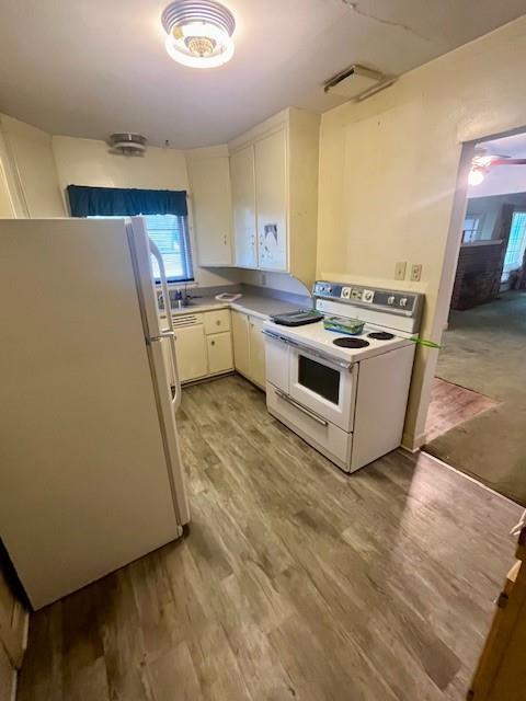 4748 Eastern Ave, Kansas City, MO 64129 - kitchen with white appliances, light wood-type flooring, and light countertops