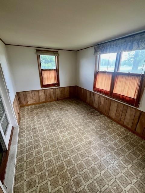 4748 Eastern Ave, Kansas City, MO 64129 - empty room featuring healthy amount of natural light, wood walls, wainscoting, and ornamental molding